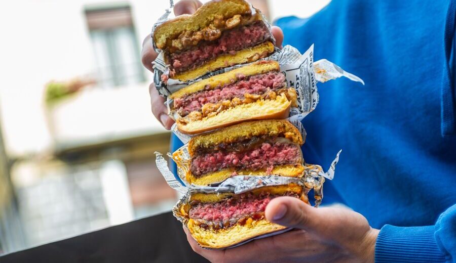 Corte de dos hamburguesas Holy apiladas, mostrando el punto de la carne